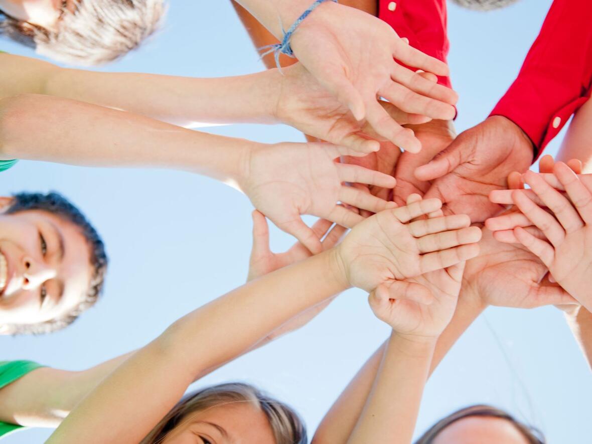 Gruppe von Kindern, die ihre Hände in die Kreismitte ausstrecken